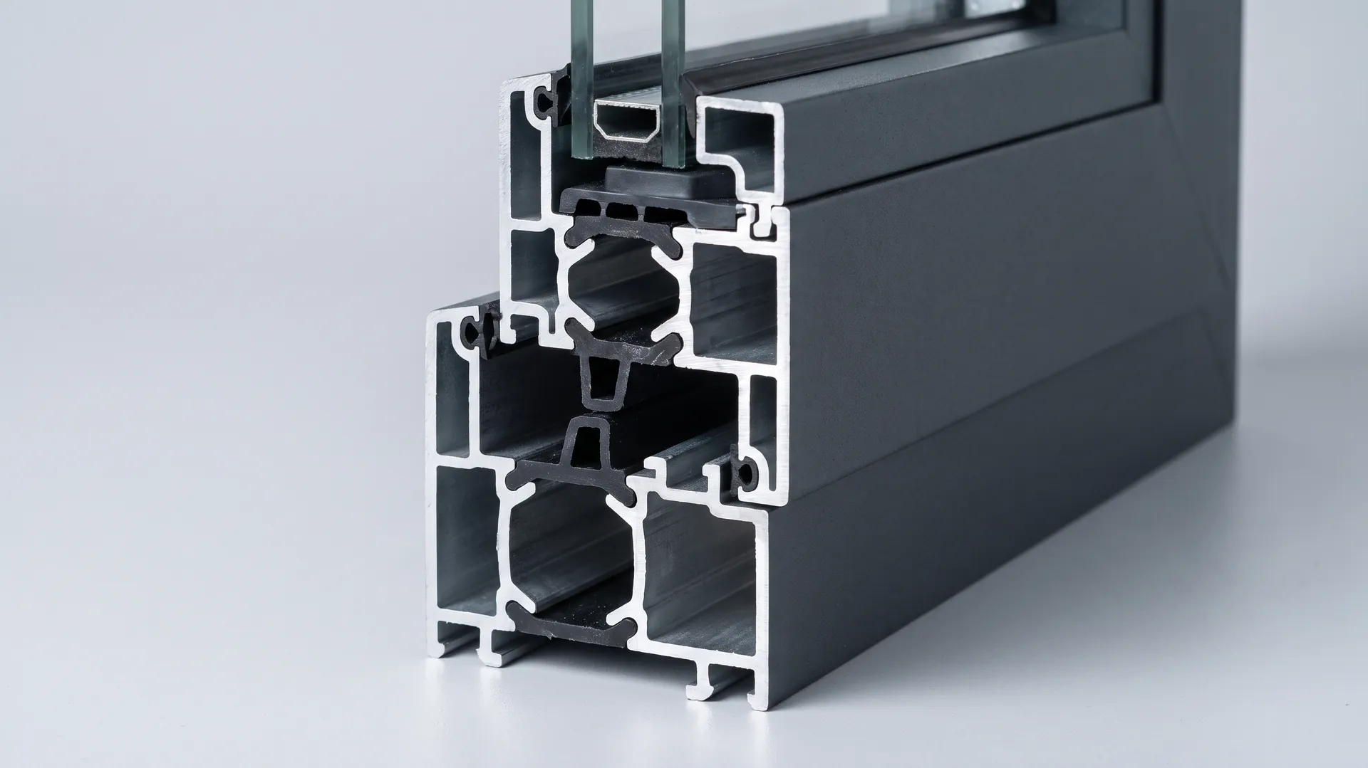 Macro view of two black gaskets compressed between an aluminium sash and frame at the closing edge