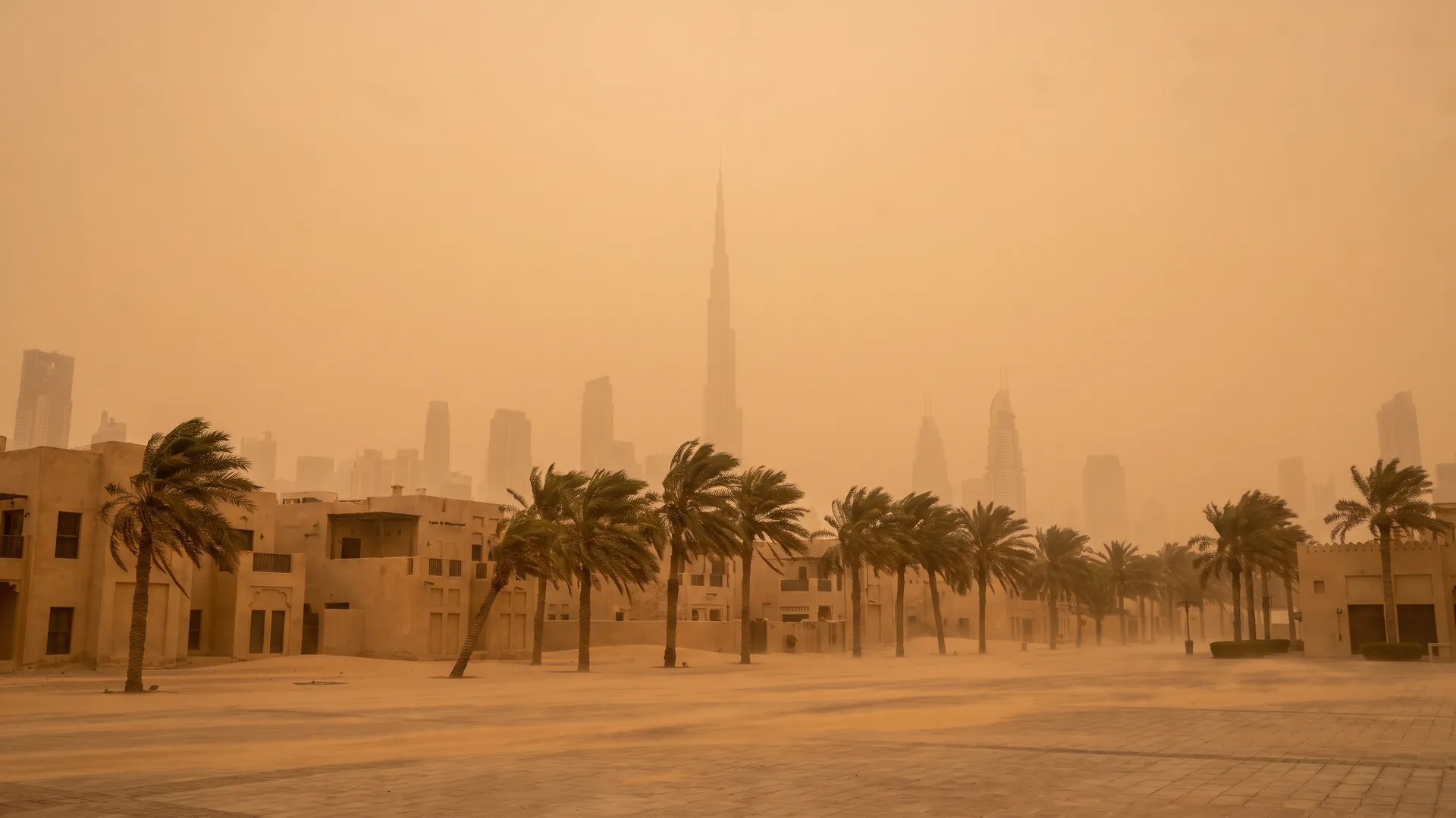 Dubai skyline reduced to faint silhouettes behind an orange dust haze during a shamal