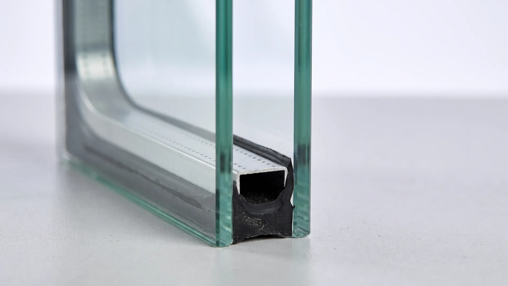 Macro view of the corner of a double glazed unit showing two panes, the spacer bar between them and the black perimeter seal