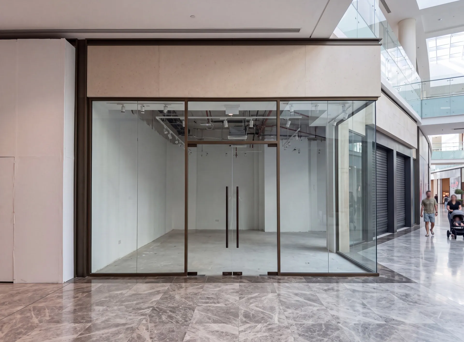 Empty unbranded shopfront in a Dubai mall with full-height glass panes in slim dark aluminium frames