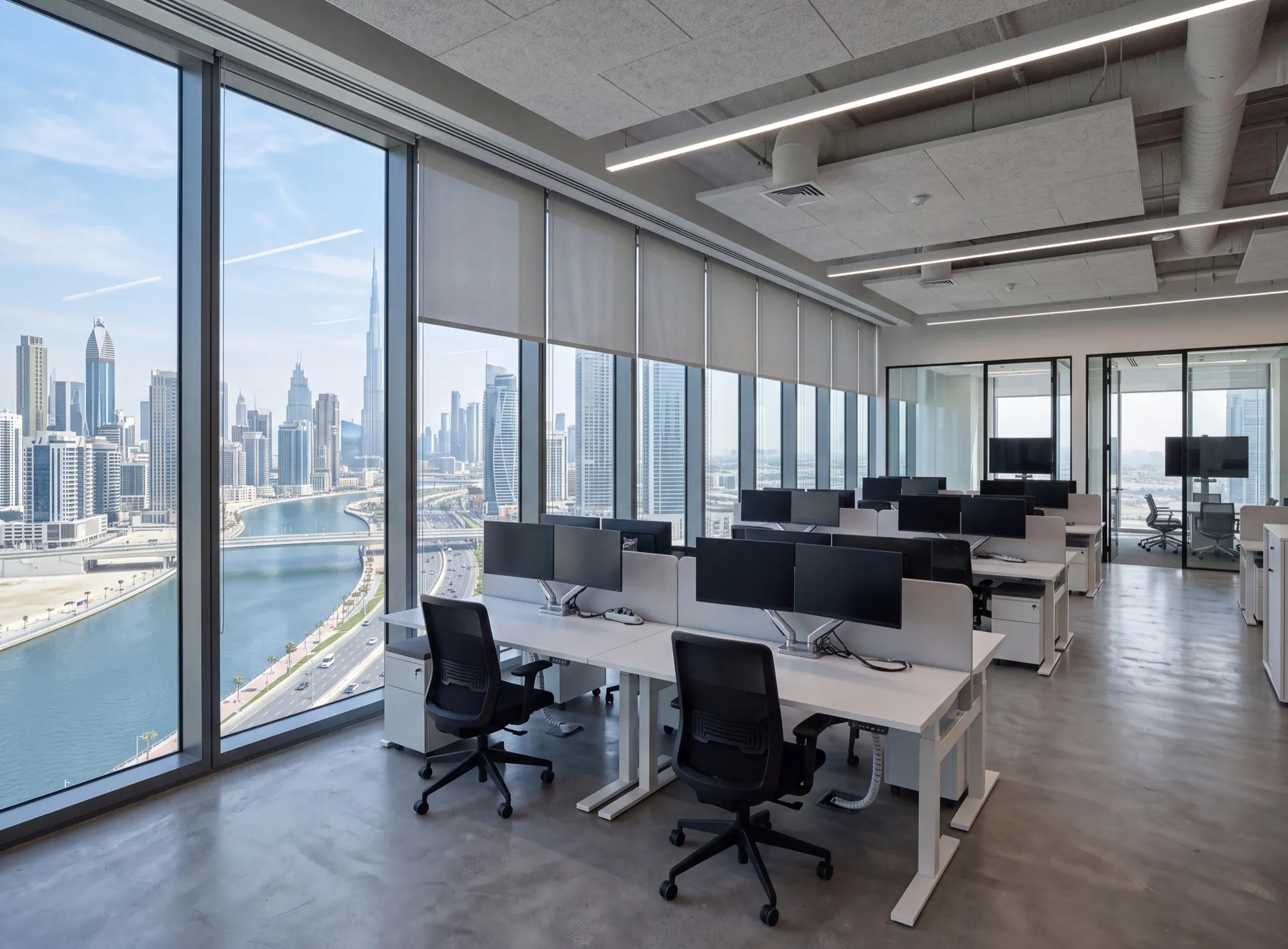 Open-plan Dubai office interior with full-height aluminium glazing along the perimeter and towers outside